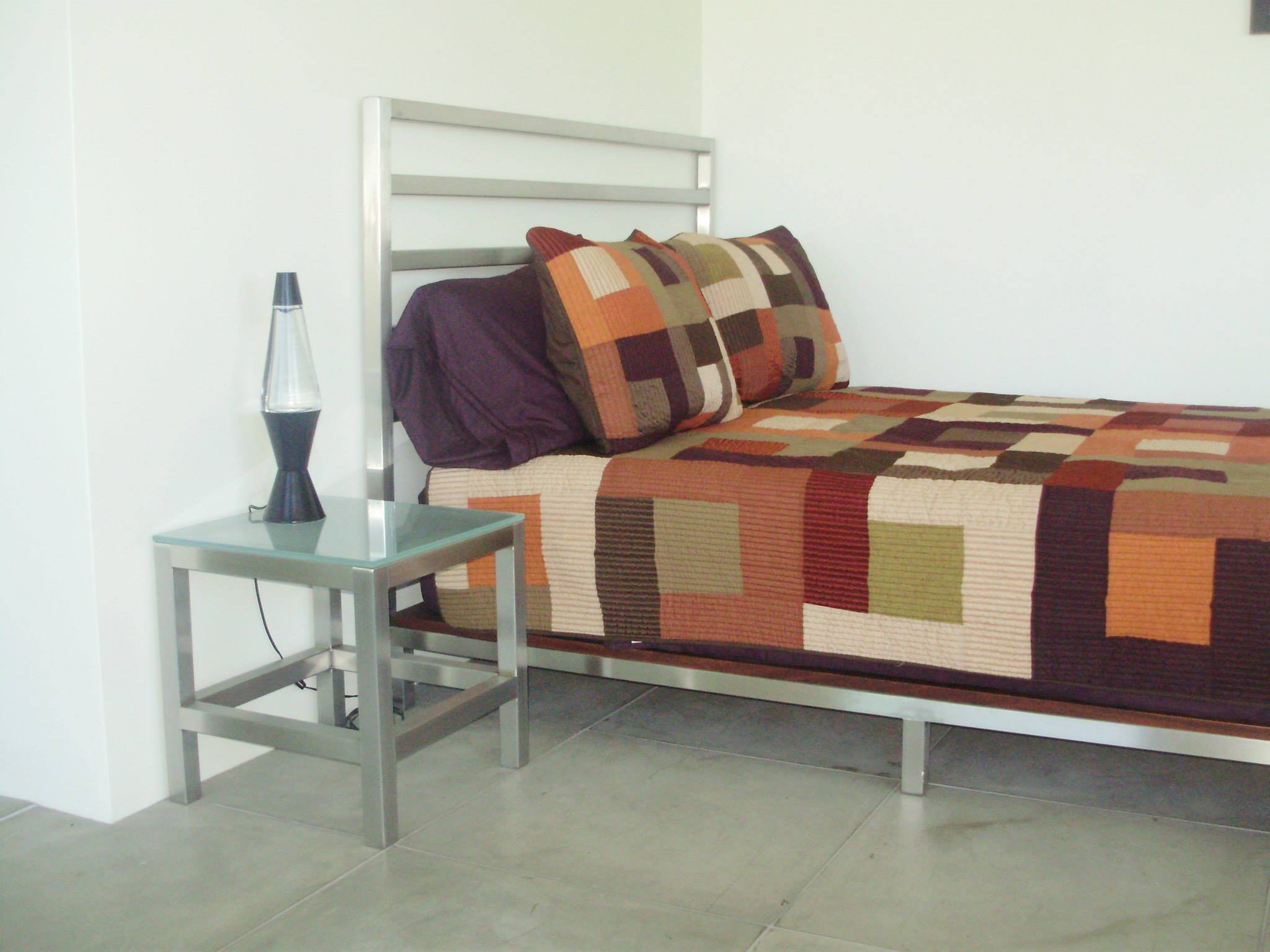 Stainless steel bed frame and matching glass-top side table