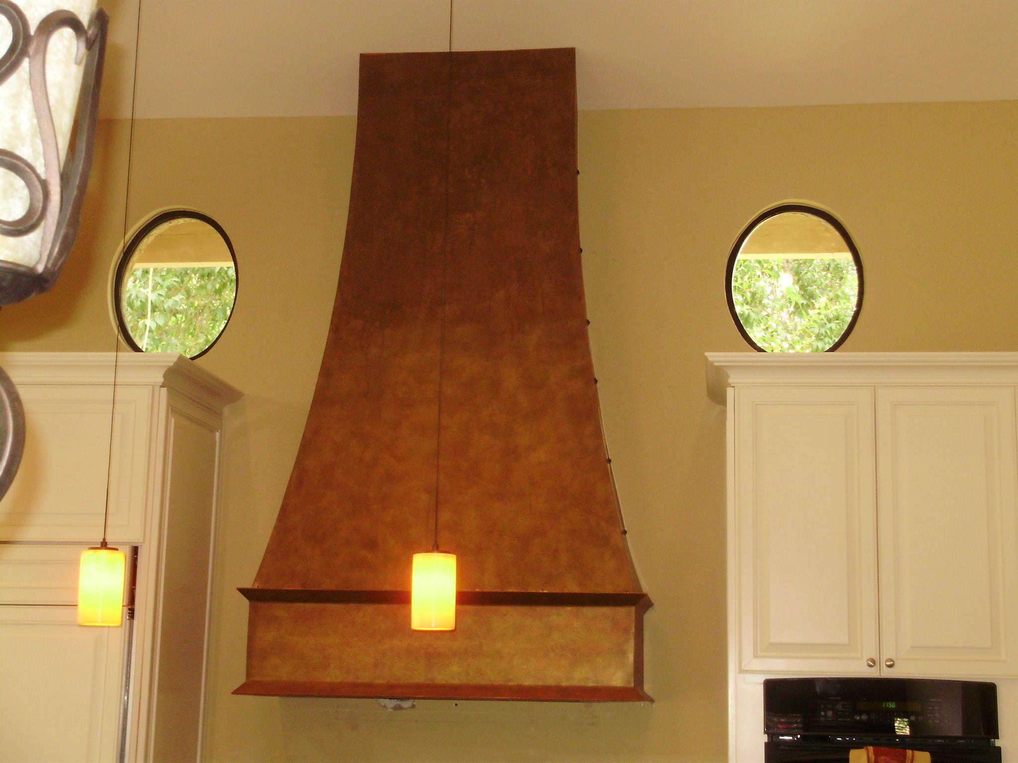 Hand-hammered copper range hood installed over kitchen range